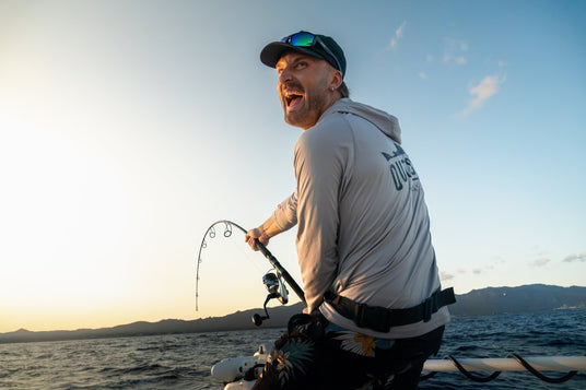 Skrikande glad fiskare drillar en tonfisk från båten med Spaniens kust i bakgrunden