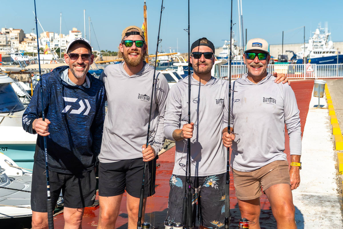 Fyra fiskare med tonfiskspön på bryggan i hamnen inför en dag med havsfiske i Spanien