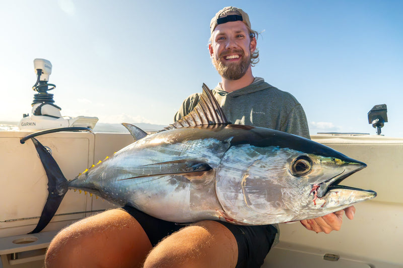 Fiskare ler mot kameran med en blåfenad tonfisk i famnen under guidat tonfiskfiske i Spanien