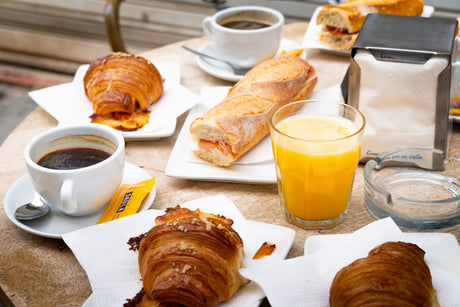 Spansk frukost med croissanter, bocadillo med serranoskinka, kaffe och apelsinjuice på kaféet