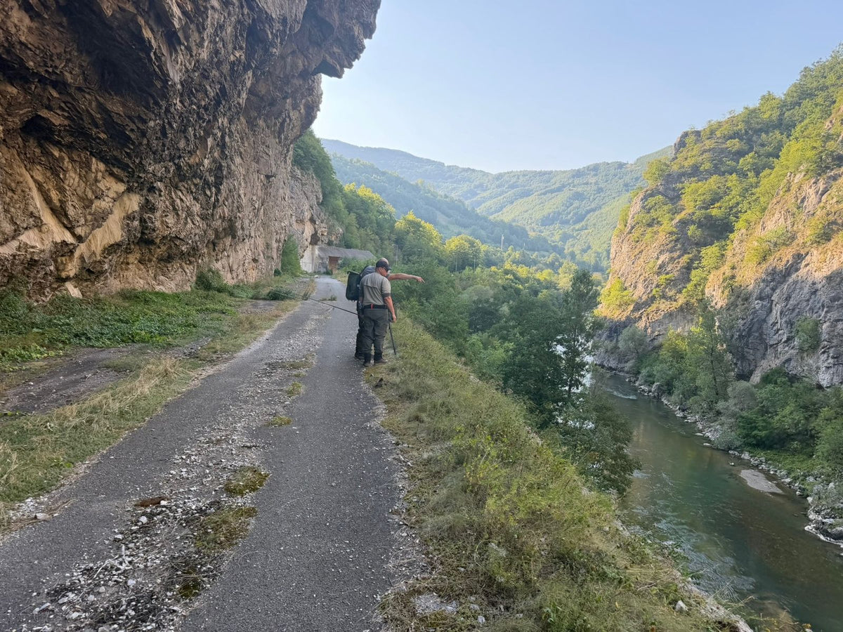 Zwei Fliegenfischer blicken von einer alten Straße unter einem Felsüberhang hinunter zum Fluss in Montenegro